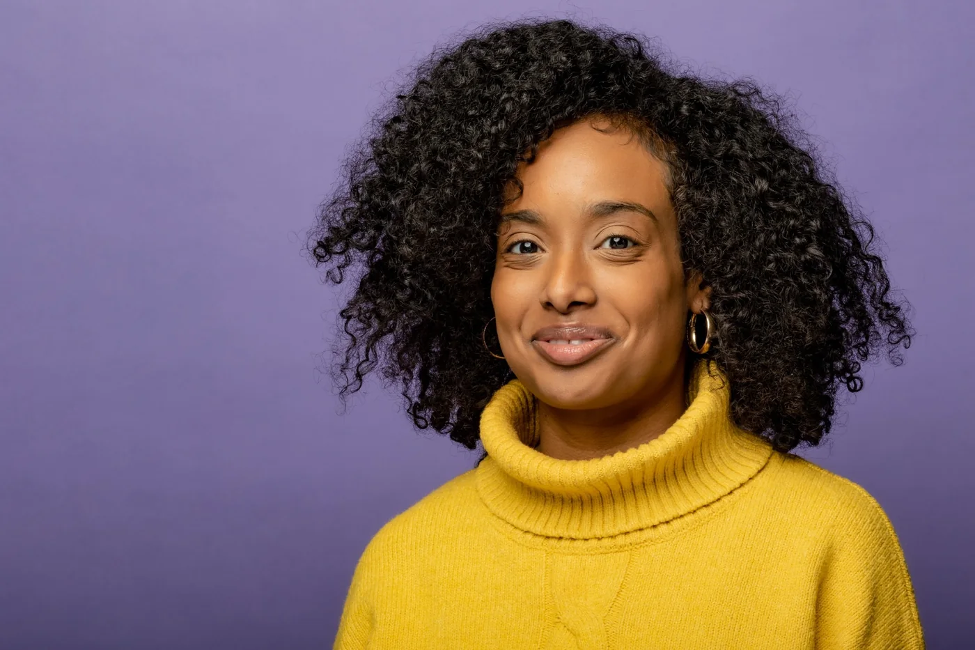 Maram Elnagheeb — portrait, in a yellow turtleneck against a violet backdrop.