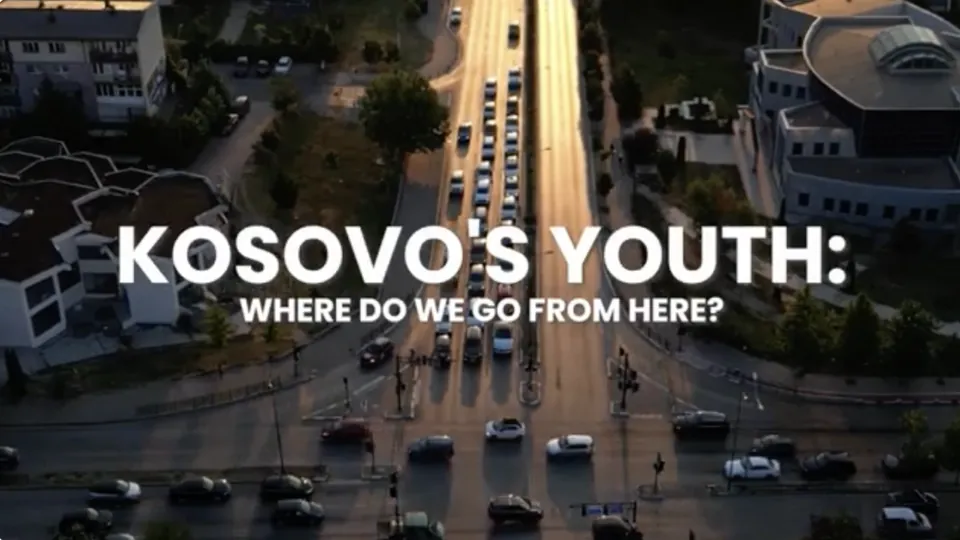 Aerial still from the documentary: a boulevard in Kosovo at golden hour, title card reading "Kosovo's Youth: Where do we go from here?"
